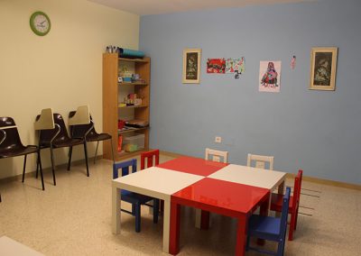 Aula infantil amb taules i bancs de diferents colors