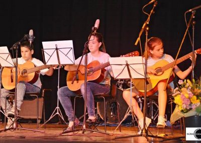 Niños tocando la guitarra sobre un escenario