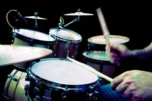 Batería en primer plano con manos y baquetas de músico