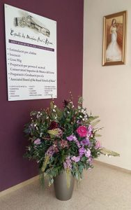 Vista interior de escuela de música con logo sobre pared y jarrón con flores