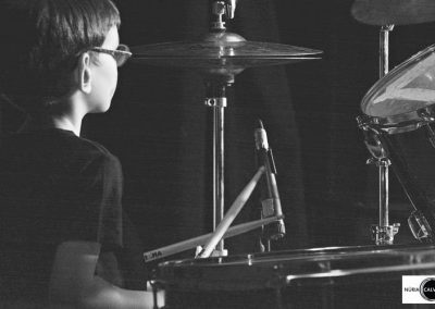 Niño tocando la batería en concierto