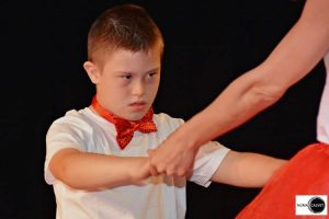 niño bailando de la mano con profesora sobre escenario