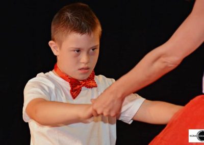 niño bailando de la mano con profesora sobre escenario