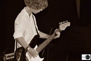 niño tocando la guitarra de pie en concierto