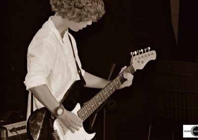 niño tocando la guitarra de pie en concierto