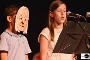 Niño con máscara y niña cantando en concierto