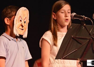 Niño con máscara y niña cantando en concierto