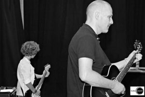 Profesor y alumno tocando la guitarra en concierto de música