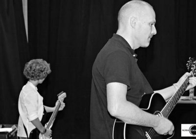 Profesor y alumno tocando la guitarra en concierto de música