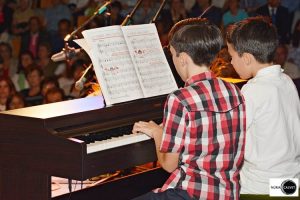 Dos niños tocando piano en concierto