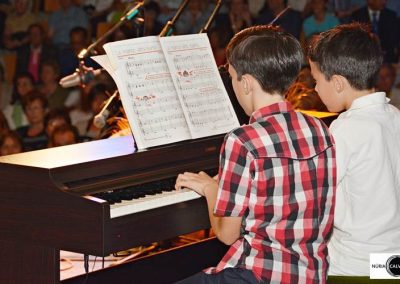 Dos niños tocando piano en concierto