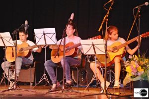 Niños tocando la guitarra sobre un escenario