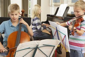Tres niños tocando violín, violoncelo y piano