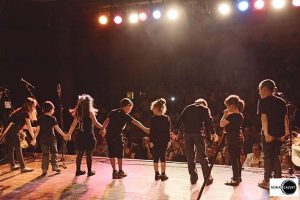 Niños saludando al público sobre un escenario