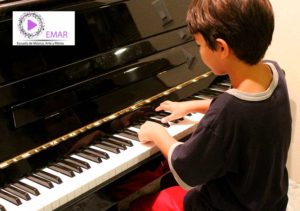 Niño que intenta aprender a tocar el piano