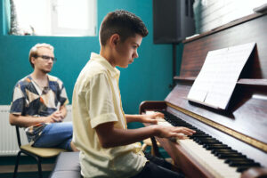 Niño tocando el piano en clase con profesor