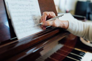 Mano de adulto marcando corrección en partitura de piano
