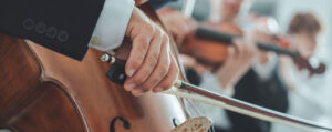 Primer plano de mano de hombre en orquesta tocando el violonchelo