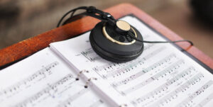 Partitura de lenguaje Musical con cascos apoyados arriba.
